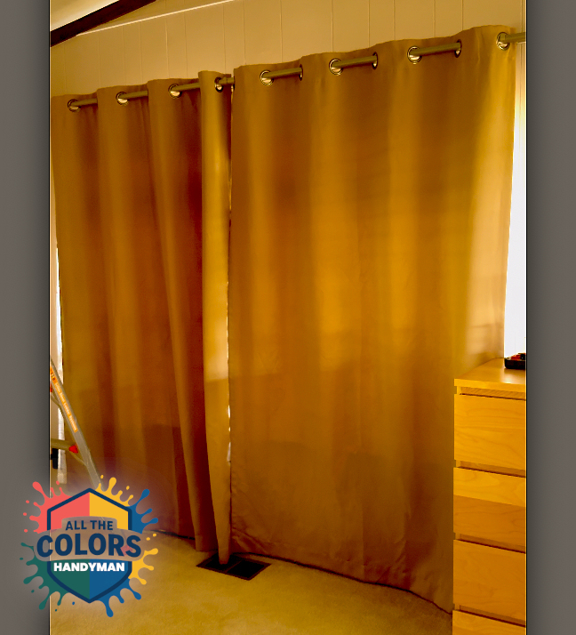 Still from vertical video showing a very wide window. The window is completely covered by a beige set of curtains. The curtains hang from grommets on a curtain rod. They hang down to about an inch off the floor. It would be easy to vacuum the floor without needing to move the curtains. 