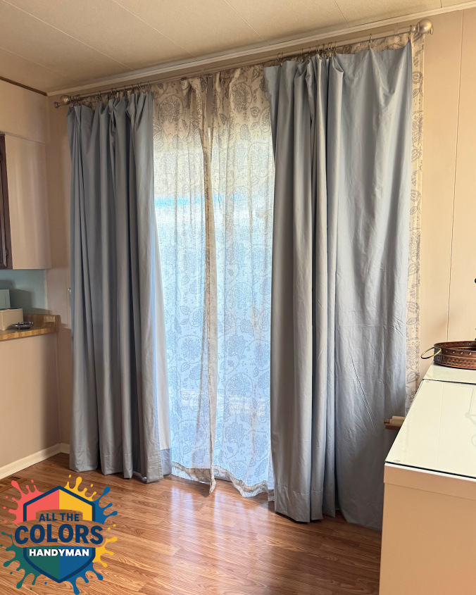 Interior photo of a patio door with curtains in front of it. A sheer grey-patterned curtain hangs closest to the door. It's mostly covered by a light blue blackout curtain. Both curtains are just kissing the floor. It looks neater than before.