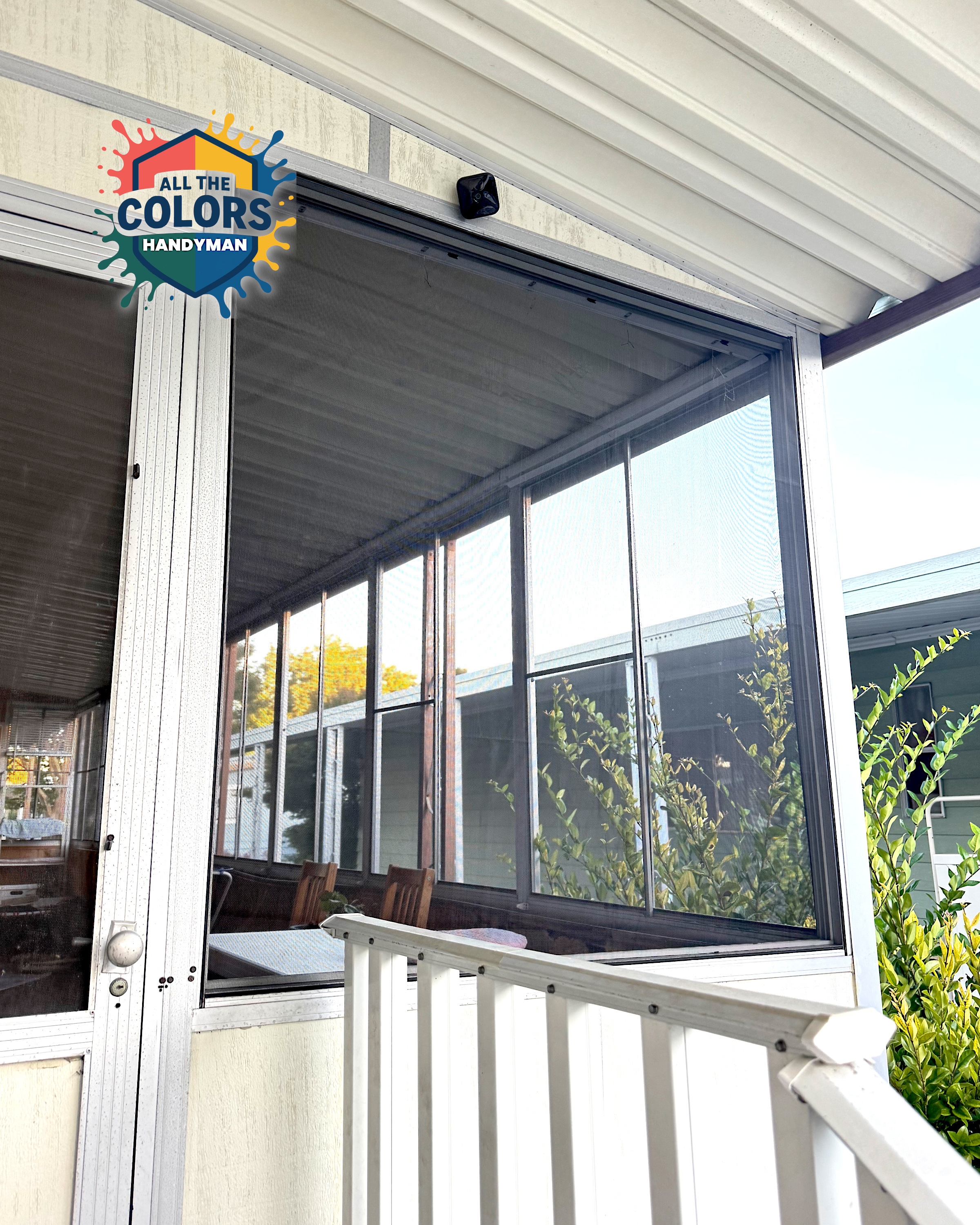 A screened porch from the outside. The oversize window is covered with sturdy screen material in black. The edges are neat and the spline is also black. 